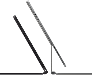 Dva iPady Pro připnuté k Magic Keyboardu, pohled z boku, tenký profil, vesmírně černá barva, reproduktory a USB‑C port, jeden napůl otevřený, druhý ve stříbrné barvě otevřený a nakloněný dozadu, takže je vidět plovoucí konzolová konstrukce klávesnice, reproduktory a mikrofon