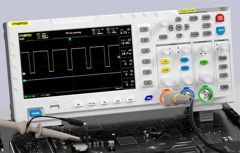 Oscyloskop z podłączonymi sondami mierzącymi sygnał na płycie elektronicznej, na ekranie widoczny wykres prostokątny.