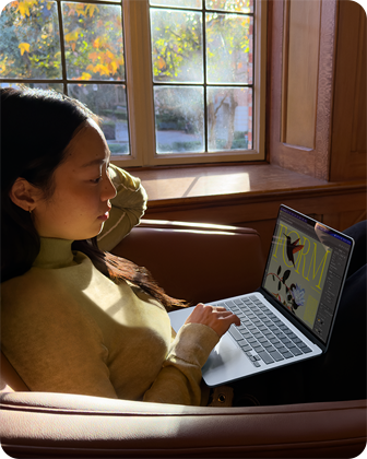 Osoba sedící v křesle používá MacBook Air