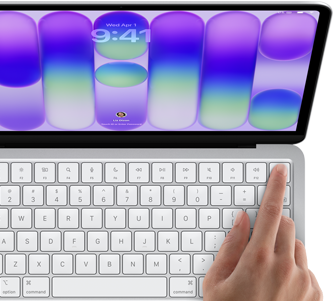 MacBook Neo, stříbrná barva, zobrazuje se přihlašovací obrazovka, něčí prst na snímači Touch ID v pravém horním rohu klávesnice
